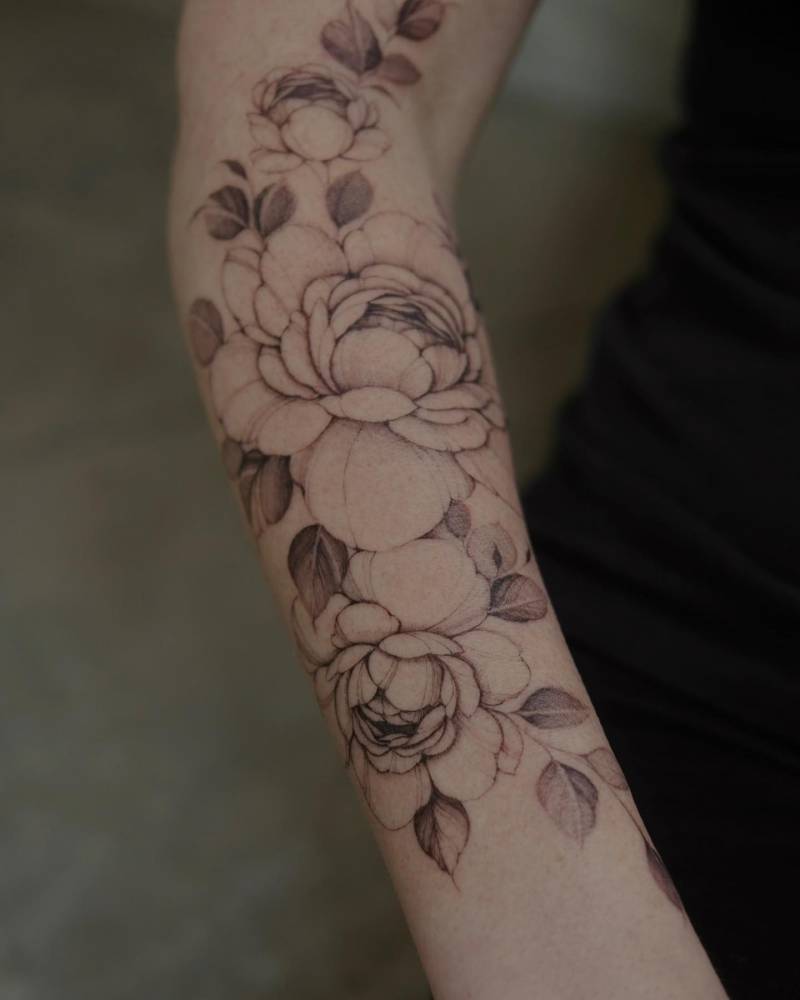Illustrative style peonies tattooed on the forearm.