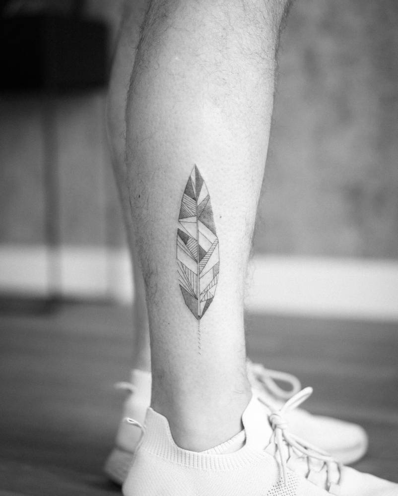 Geometric style feather tattoo located on the shin.