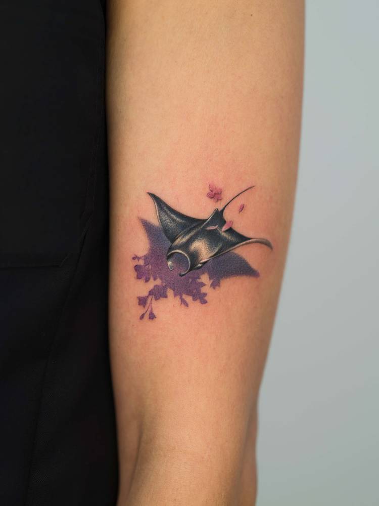 Manta ray and flowers tattooed on the upper arm.