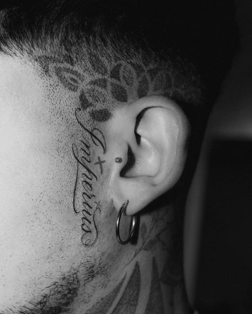 Script font word "imperius" tattooed on the face.