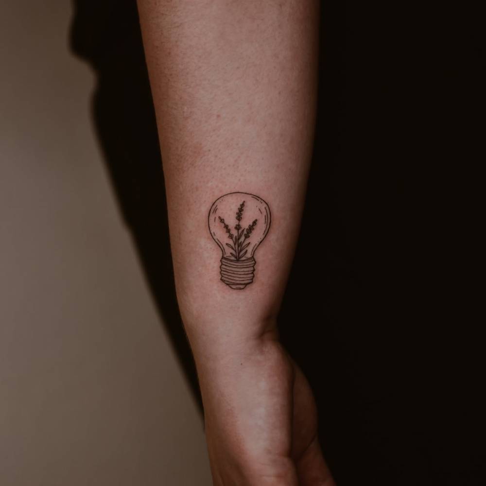 Illustrative style light bulb and lavender tattoo located on the wrist.