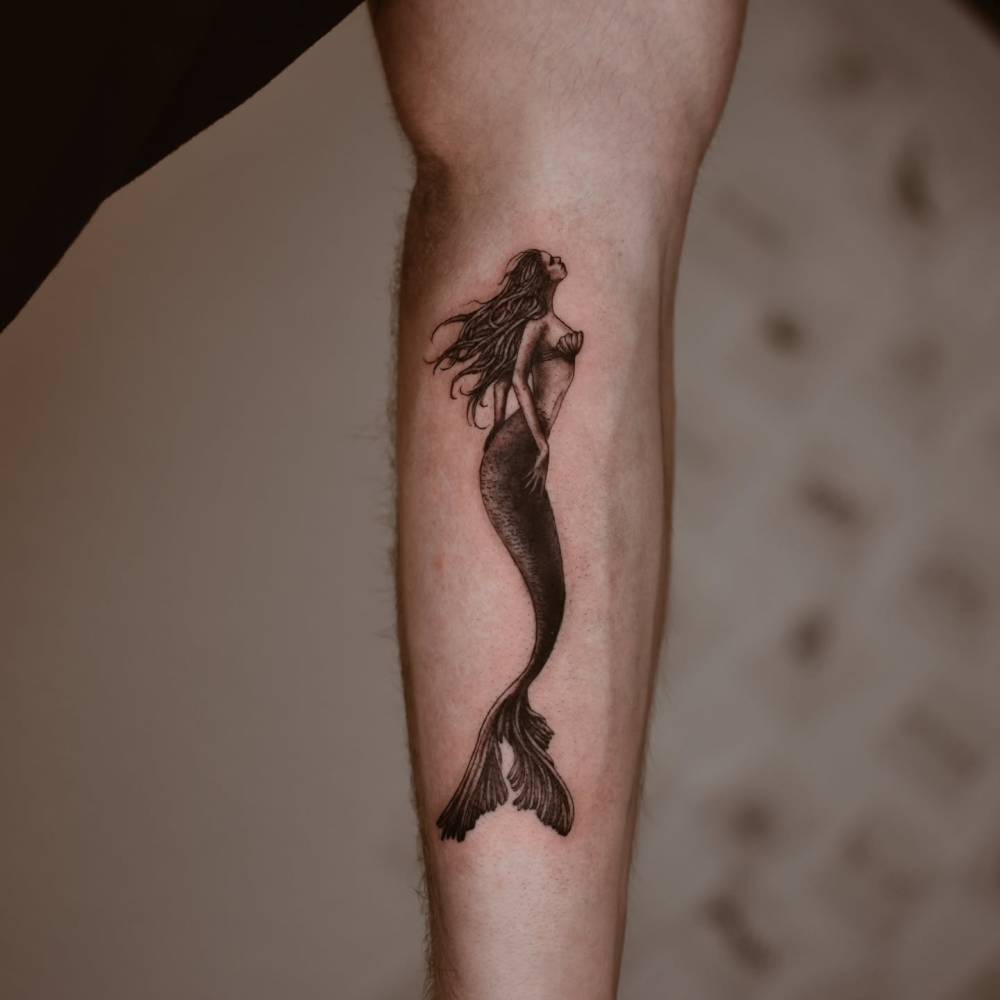 Mermaid tattoo in illustrative style located on the inner forearm.