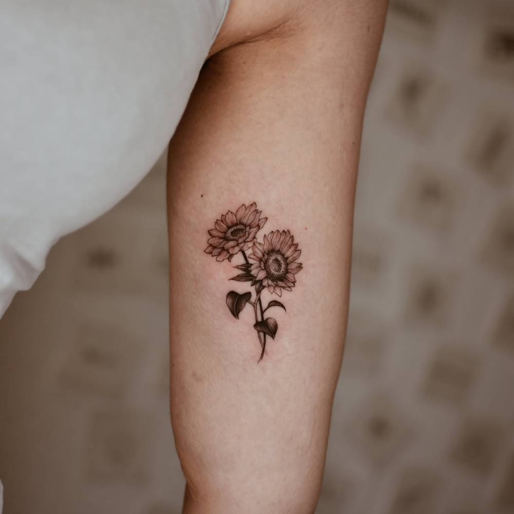 Sunflower couple tattooed on the inner arm, done in illustrative style.