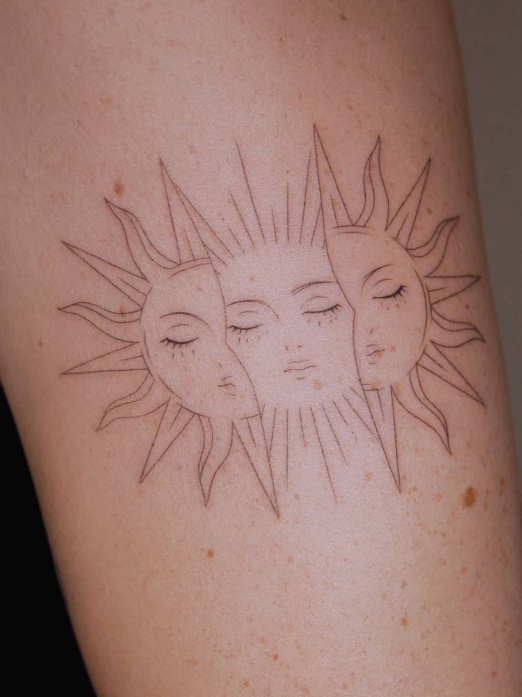 Inti sun tattoo in fine line style placed on the upper arm.