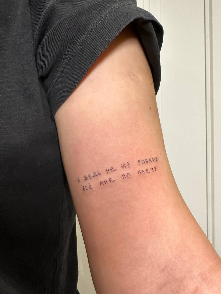 Russian lettering tattoo located on the bicep.