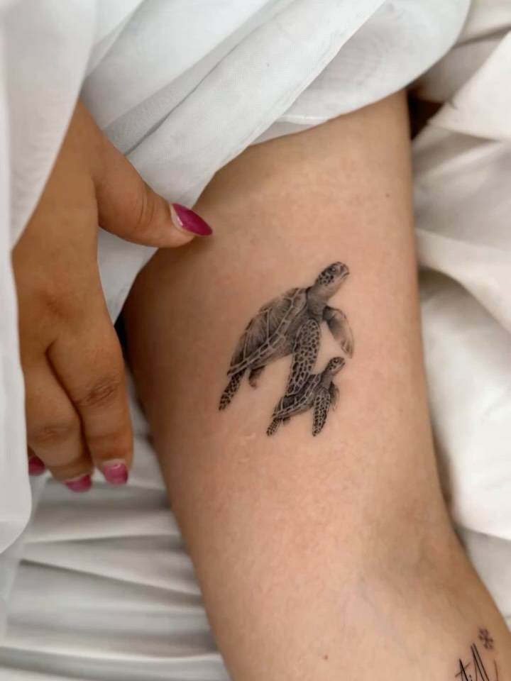 Micro-realistic style turtles tattooed on the inner arm.