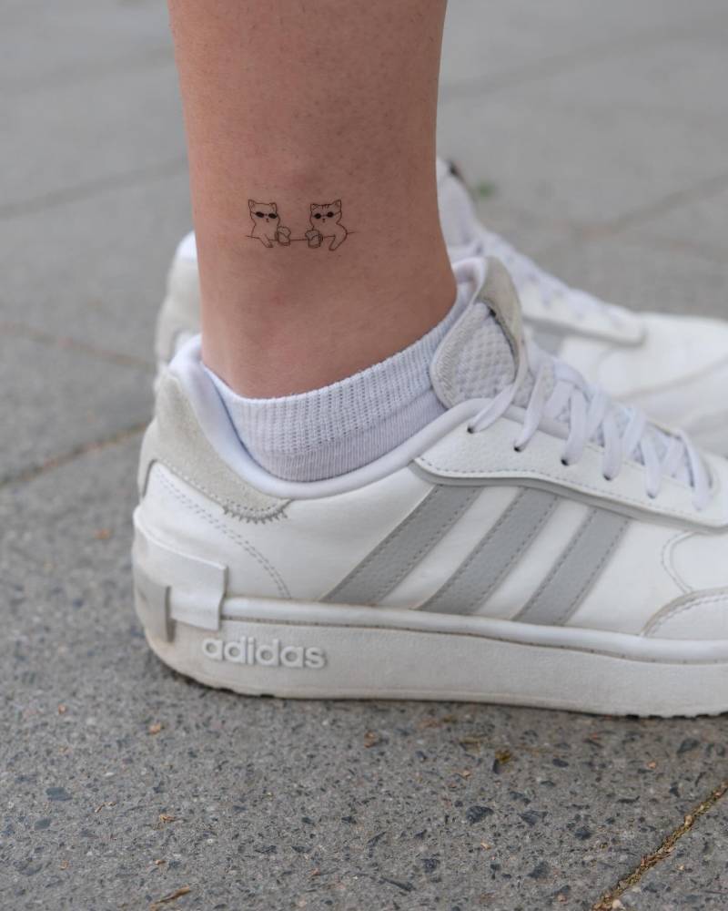 Fine line style cats tattoo located on the ankle.
