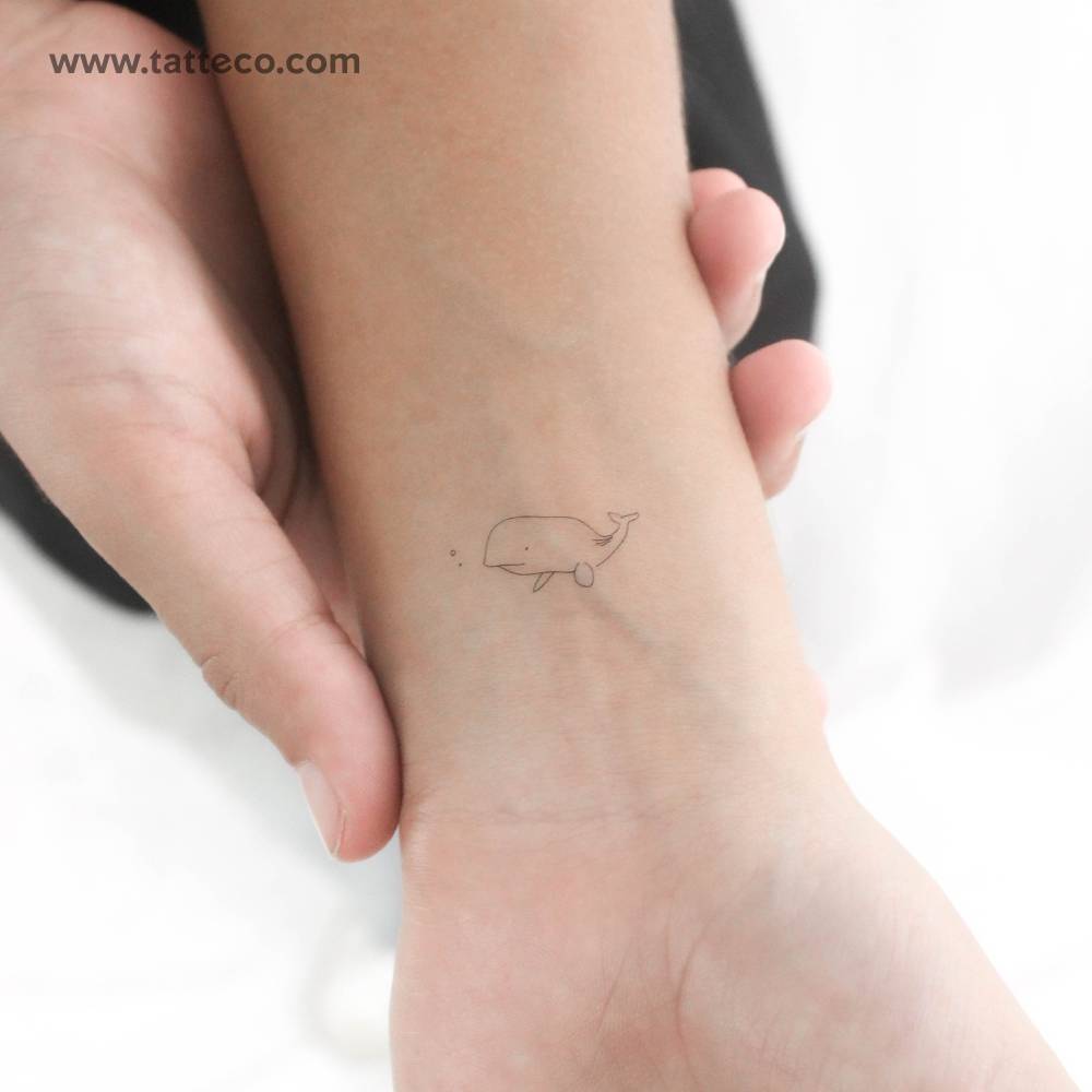 Minimalist fine line whale temporary tattoo located on the wrist.