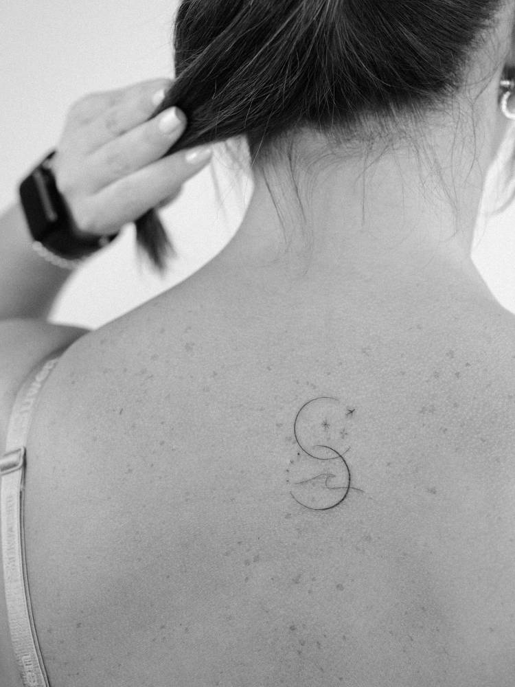 Airplane and wave tattoo located on the upper back, done in fine line style.