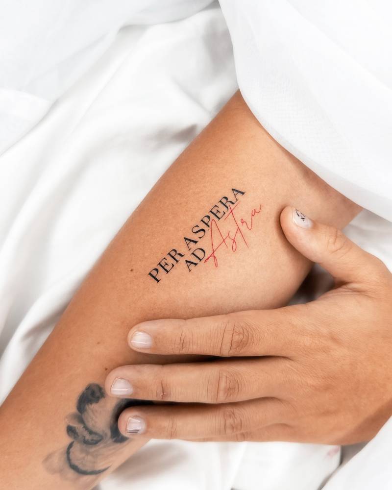 "Per aspera ad astra" lettering tattoo located on the inner forearm.
