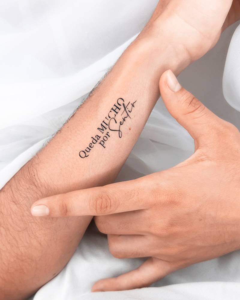 "Queda mucho por sentir" lettering tattoo located on the wrist.