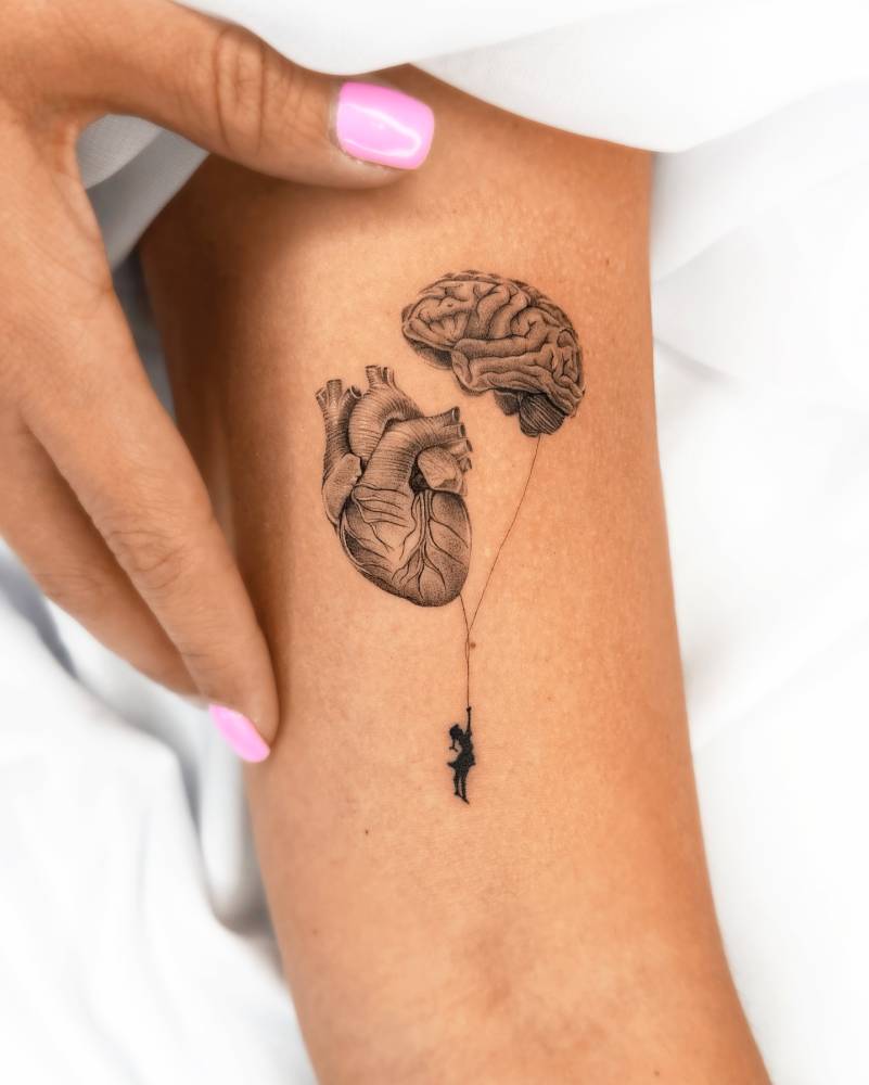Heart vs brain balloons tattooed on the bicep.