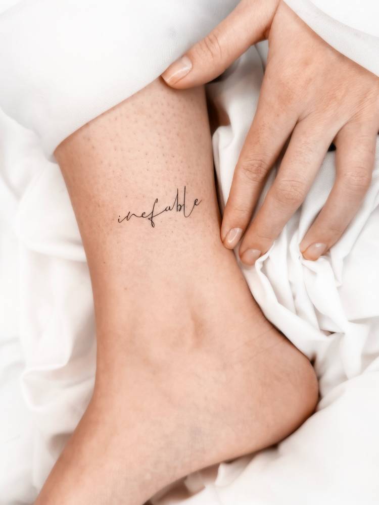 Word "inefable" lettering tattoo placed on the ankle.