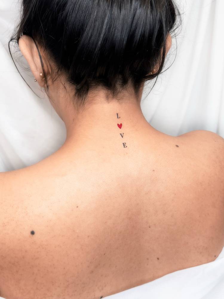 Word "love" tattoo in serif font located on the back of the neck.
