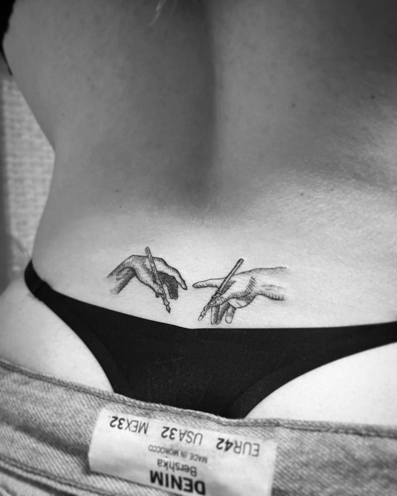 'Creation of Adam' hands tattooed on the lower back.