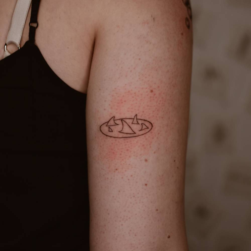 Minimalistic style shark fins tattooed on the tricep.