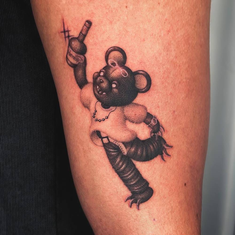 Teddy bear tattoo in dotwork style located on the upper arm.