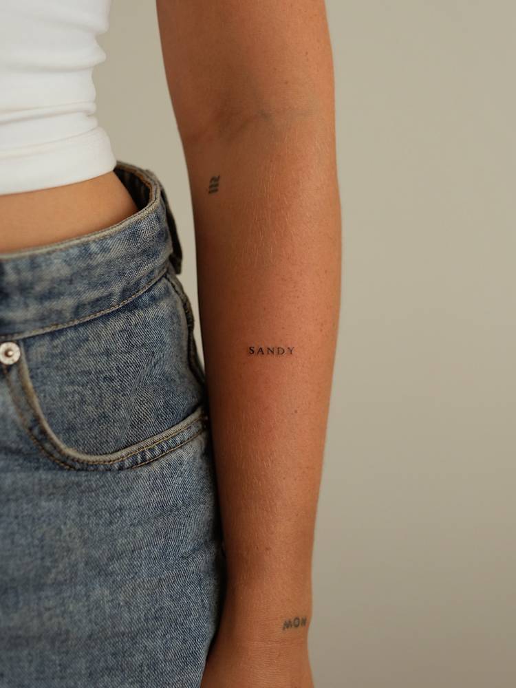 Lettering tattoo of the name "Sandy" in serif font.