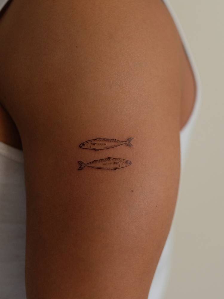 Two opposite fish tattoo located on the upper arm.