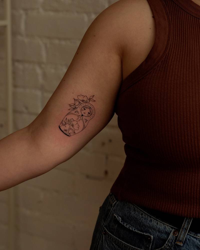 Matryoshka doll tattoo in fine line style located on the inner arm.