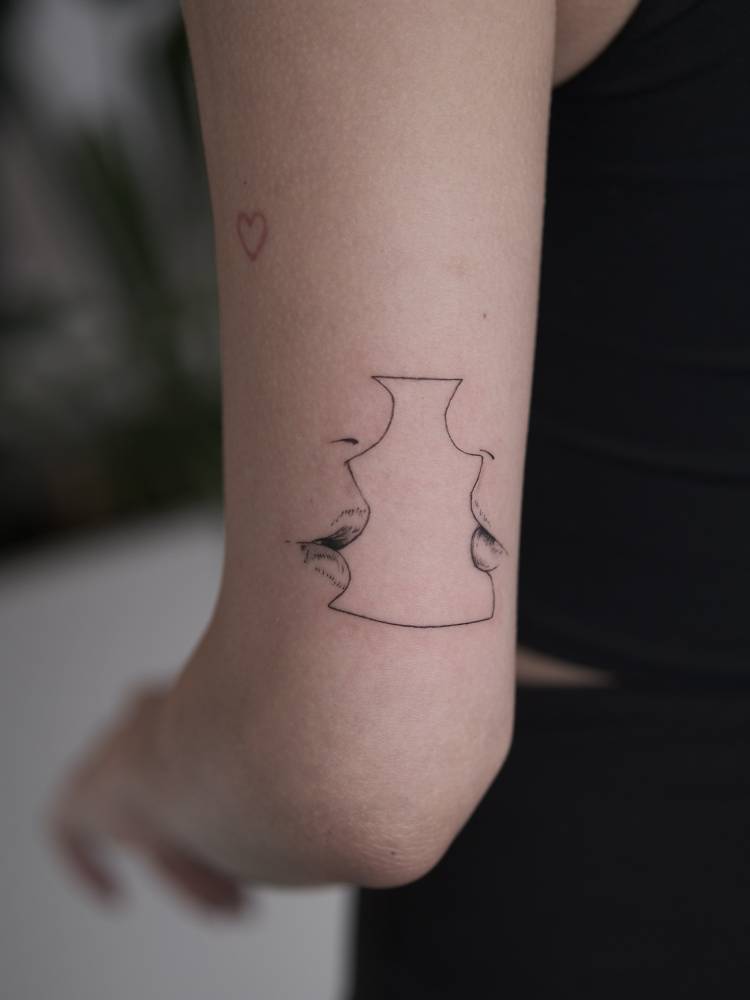 Illustrative style kiss tattoo located on the tricep.