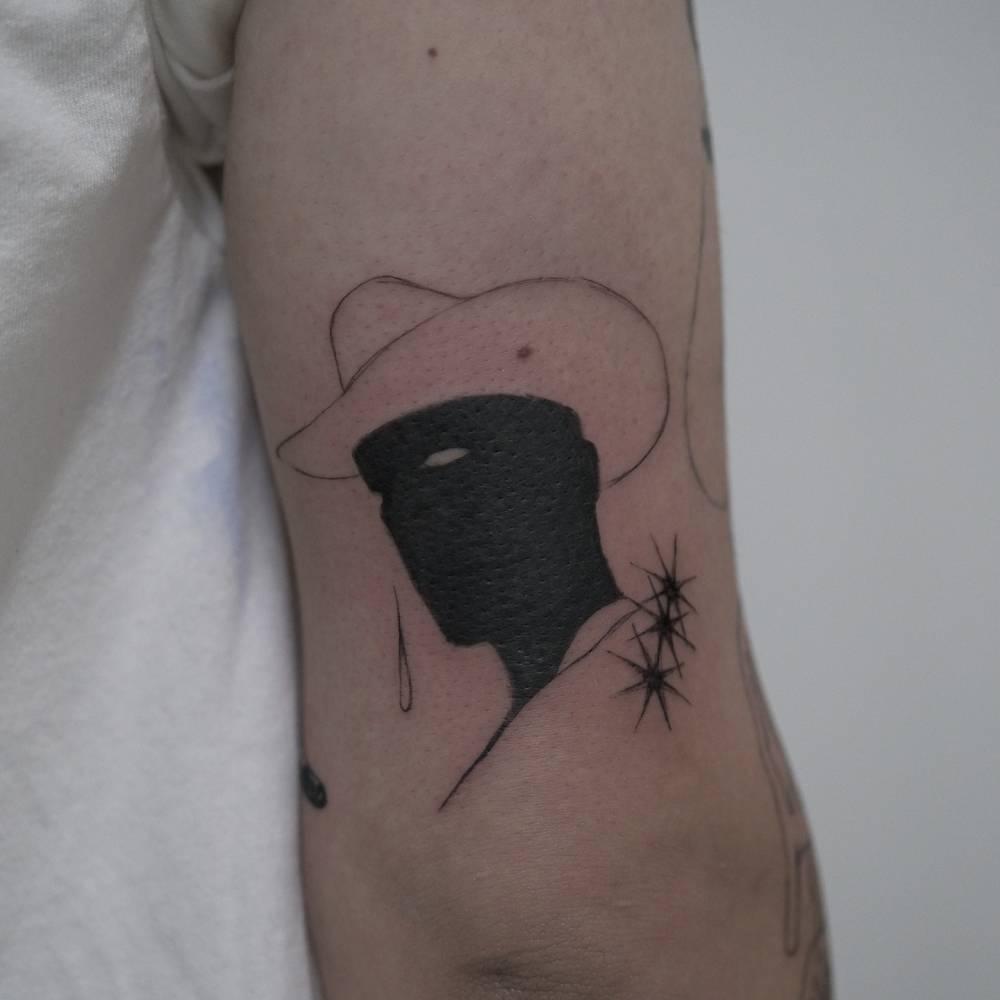 Blackwork style cowboy portrait tattoo located on the tricep.
