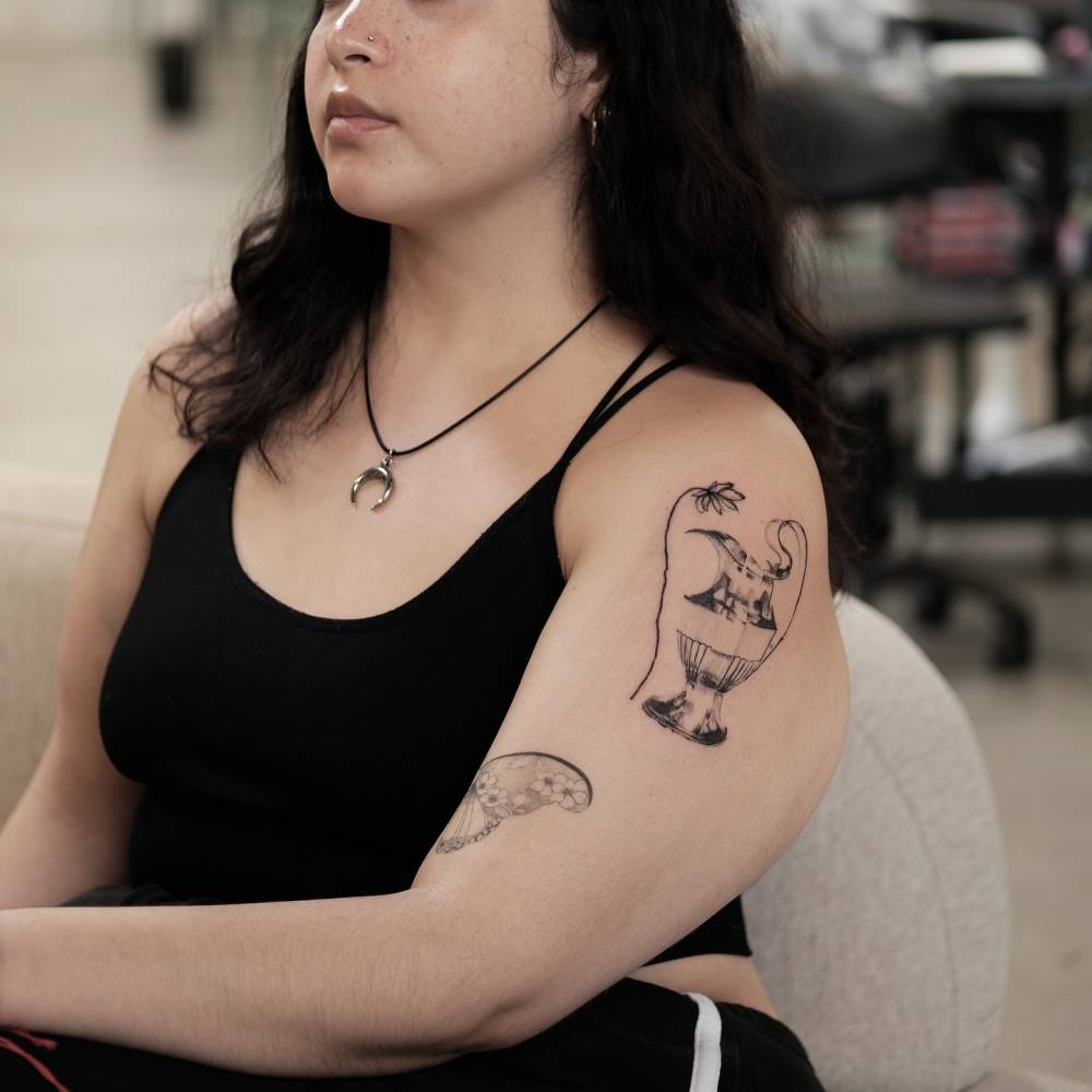 Lotus flower and vase tattoo in blackwork style.