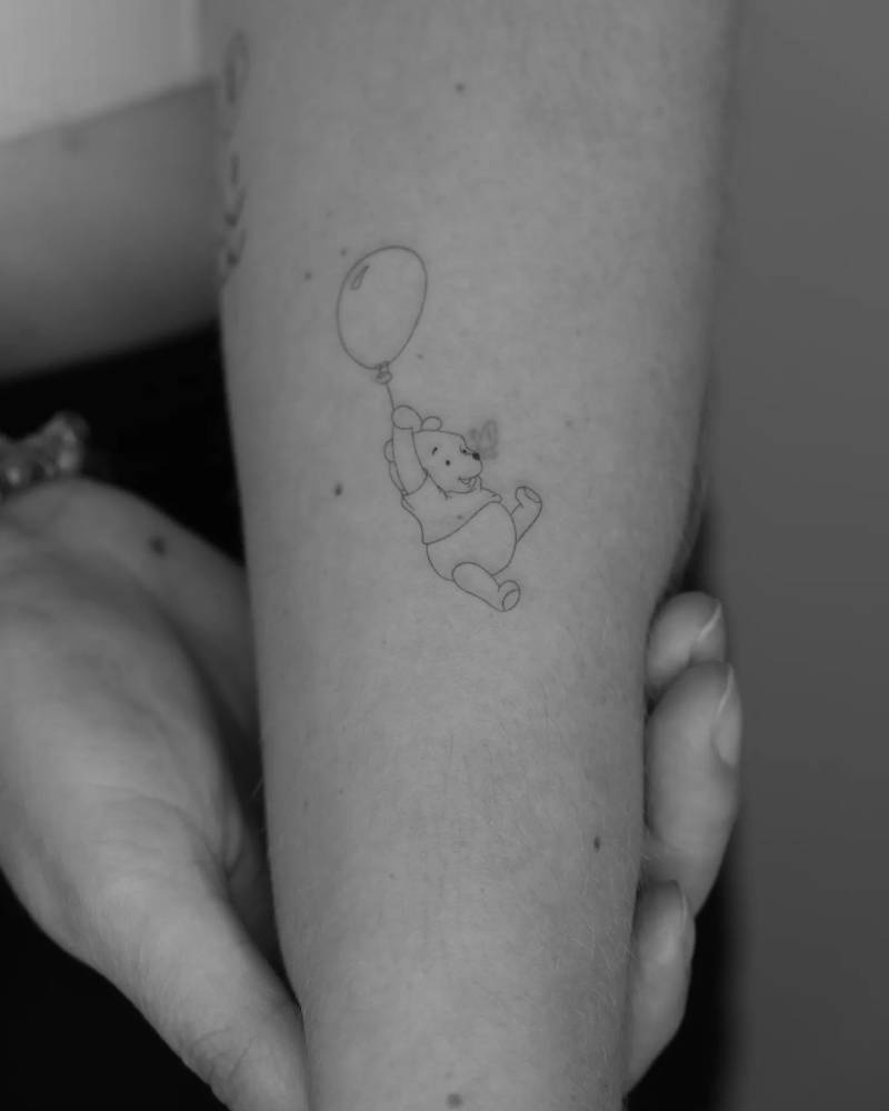Fine line style Pooh Bear tattoo located on the forearm.