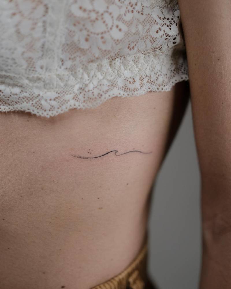 Minimalistic style wave tattoo placed on the rib.