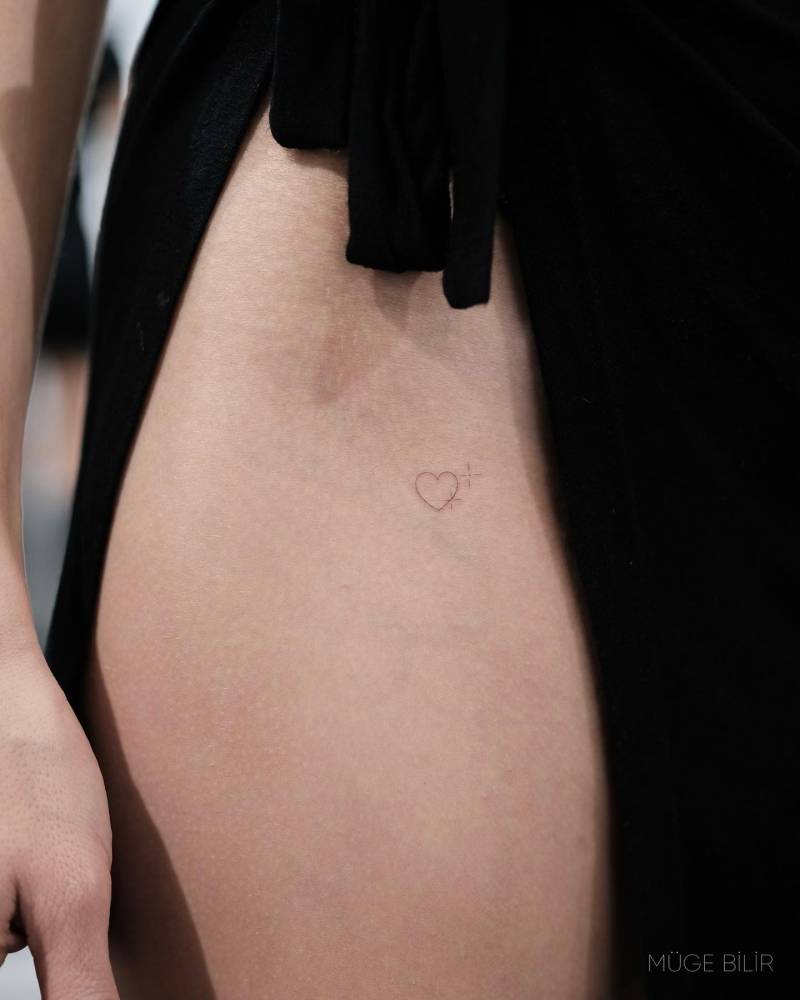 Minimalistic style heart tattoo placed on the pelvis.