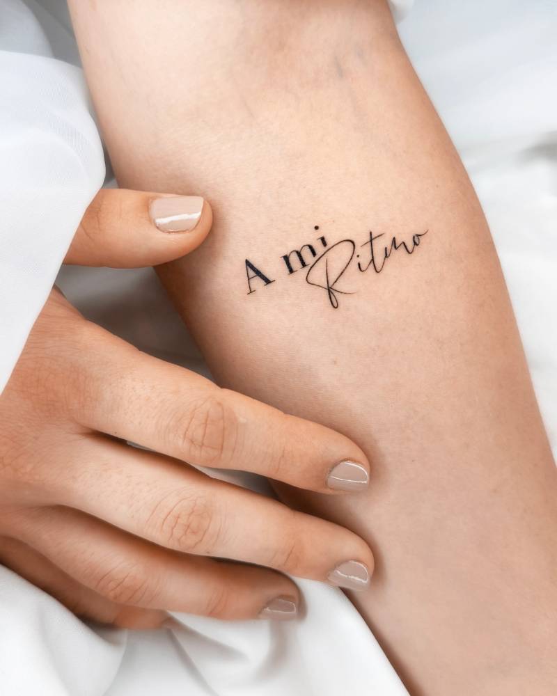 Lettering tattoo that says "a mi ritmo" located on the inner forearm.