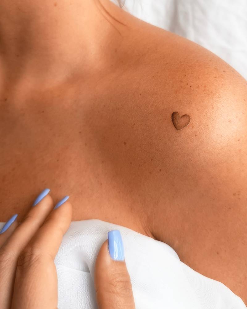 Tiny spectrum heart tattoo located on the shoulder.