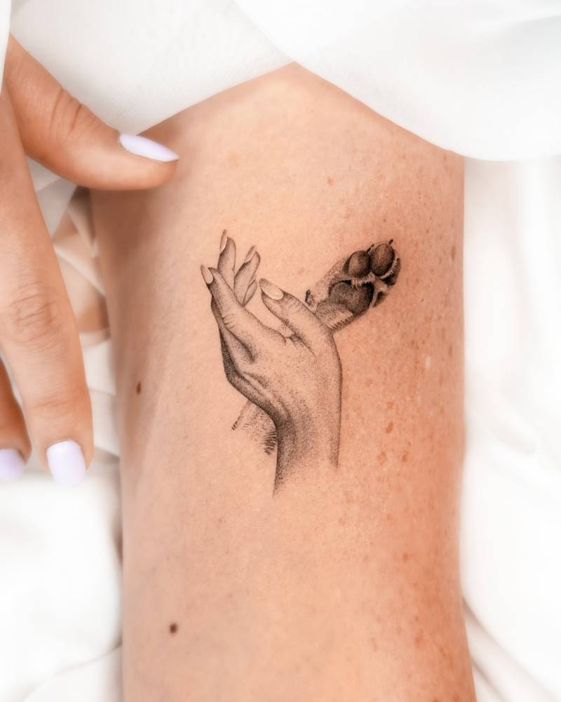 Hand and paw tattoo in micro-realistic style located on the bicep.