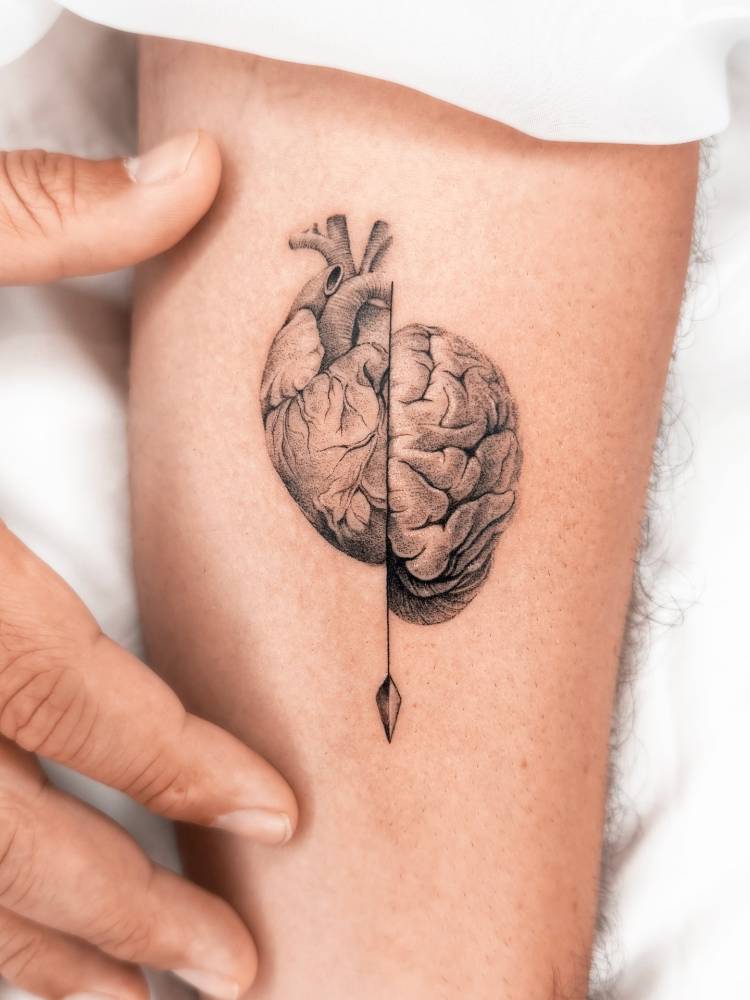 Micro-realistic style heart vs. brain tattoo done on the inner forearm.