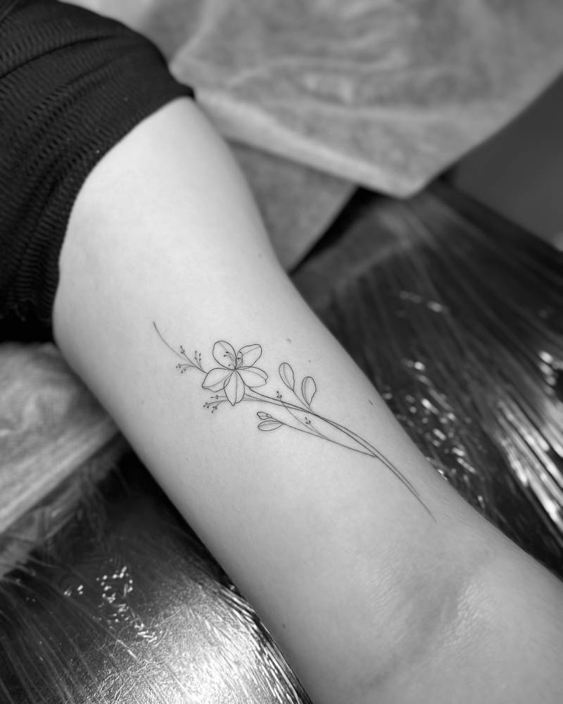 Flower tattoo in fine line style placed on the bicep.