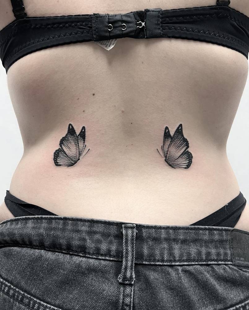 Blackwork style butterfly couple tattoo located on the lower back.