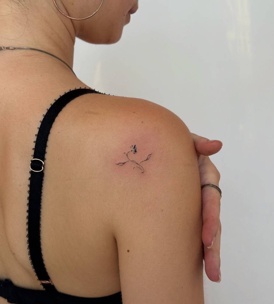 Fine line style flower tattoo located on the shoulder blade.