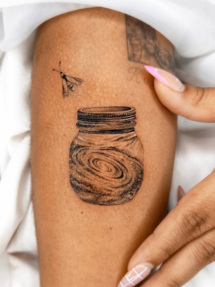 Micro-realistic style galaxy in a jar tattoo located on the inner forearm.