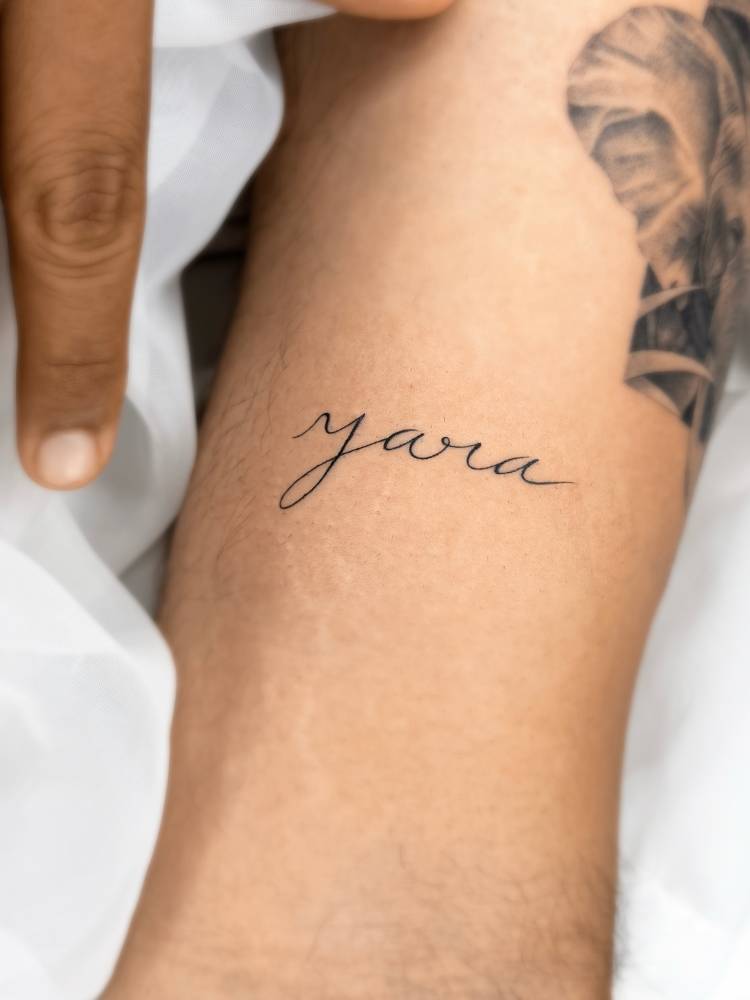 Lettering tattoo of the name "Yara" located on the bicep.