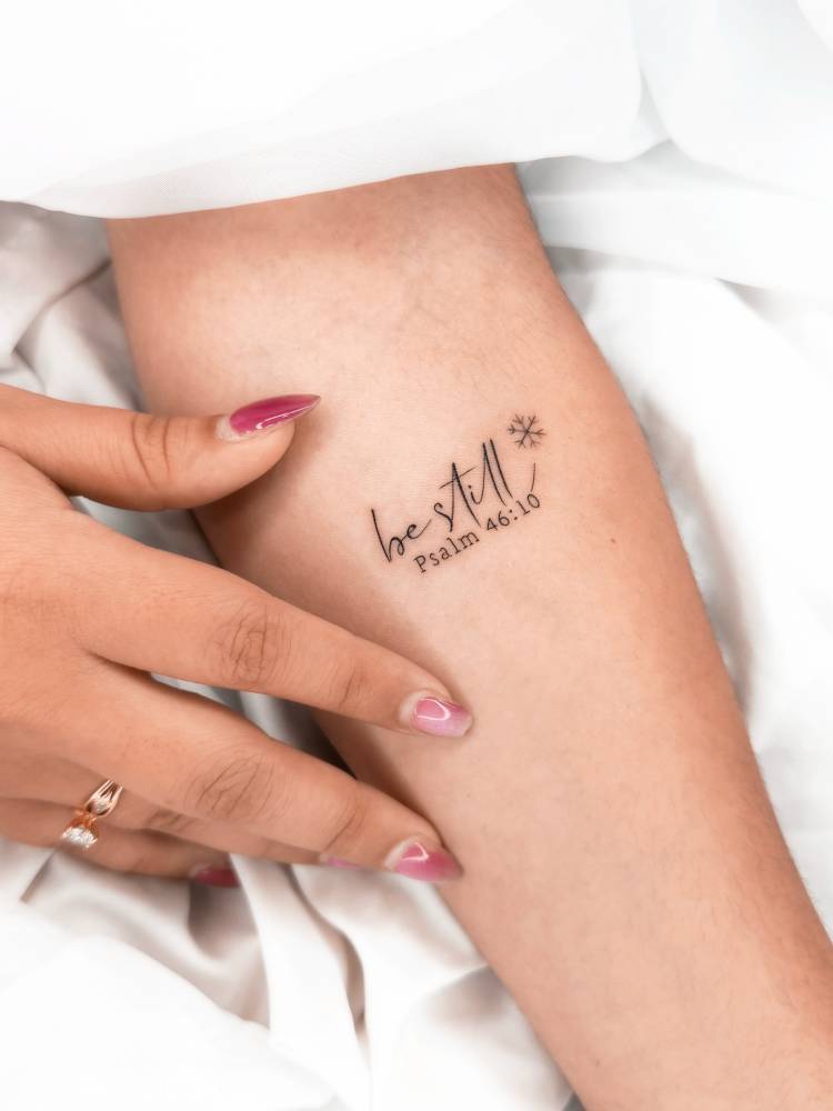 "Be still" psalm 46:10 tattooed on the inner forearm.