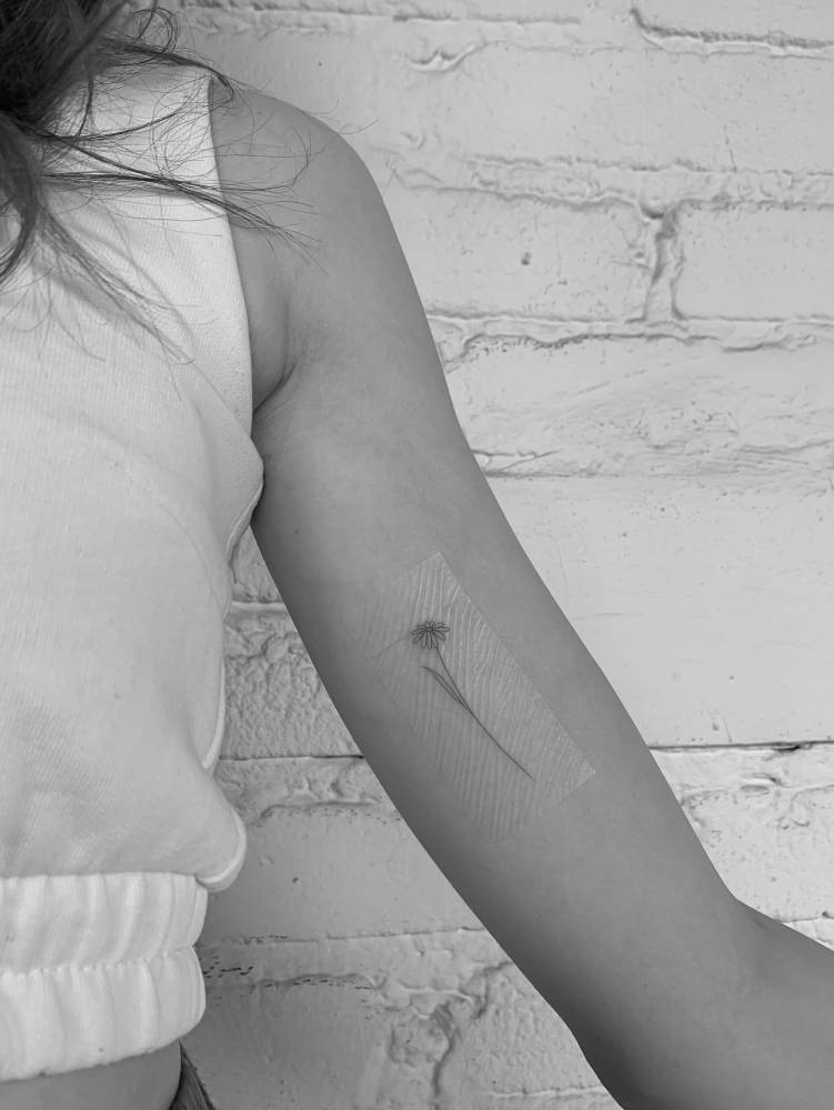 Fine line style flower tattoo located on the inner arm.