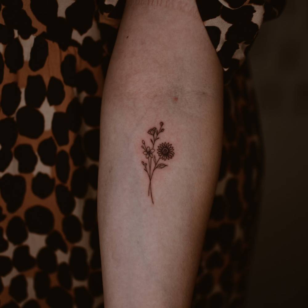 Flower bouquet tattoo in illustrative style located on the inner forearm.