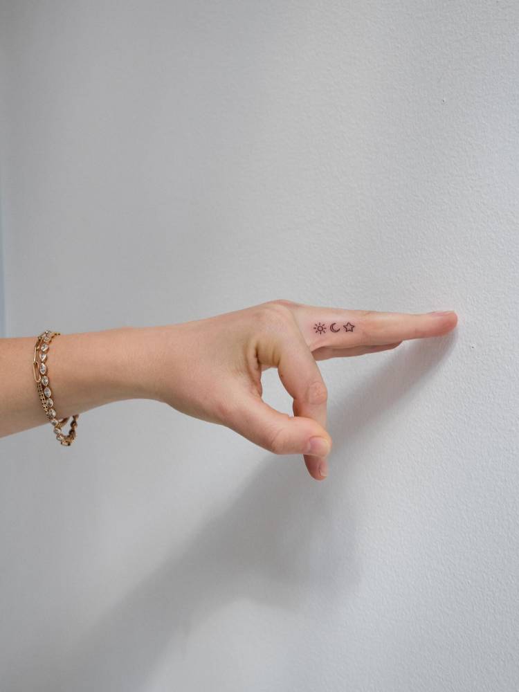 Sun, moon and star tattoo in minimalistic style located on the finger.