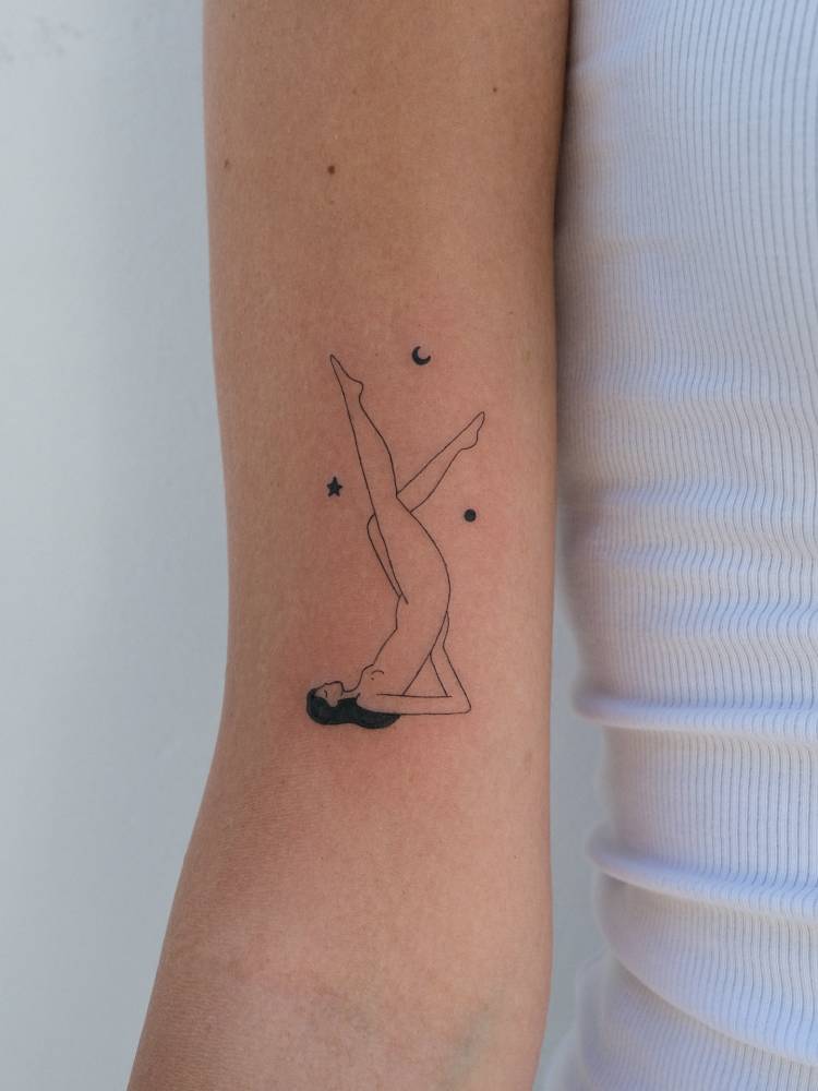 Nude woman tattoo in fine line style located on the bicep.