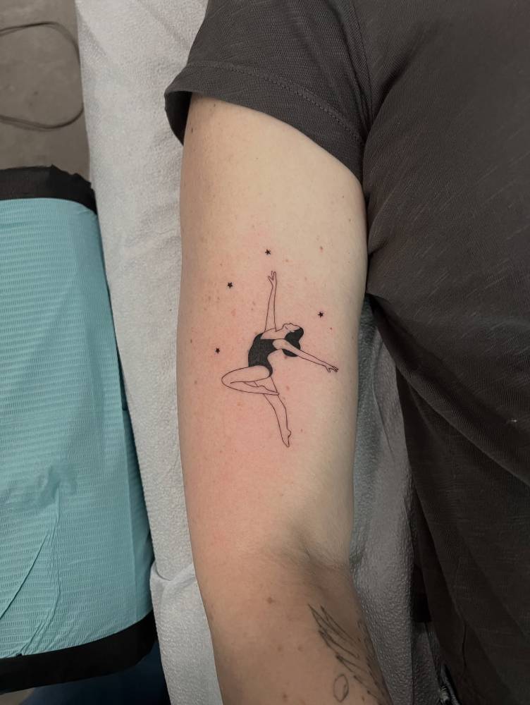 Ballerina tattoo in illustrative style located on the upper arm.