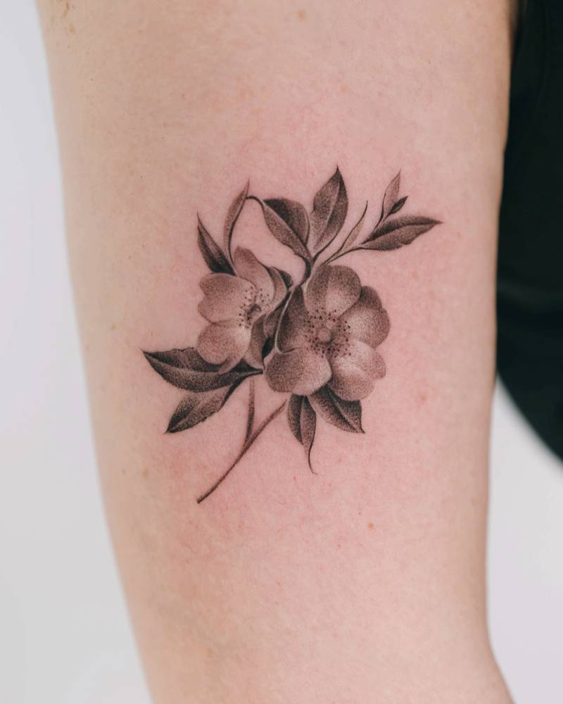 Micro-realistic style dog rose tattoo located on the upper arm.