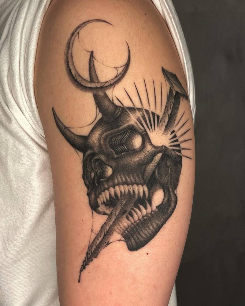 Blackwork style skull and nail tattoo placed on the upper arm.