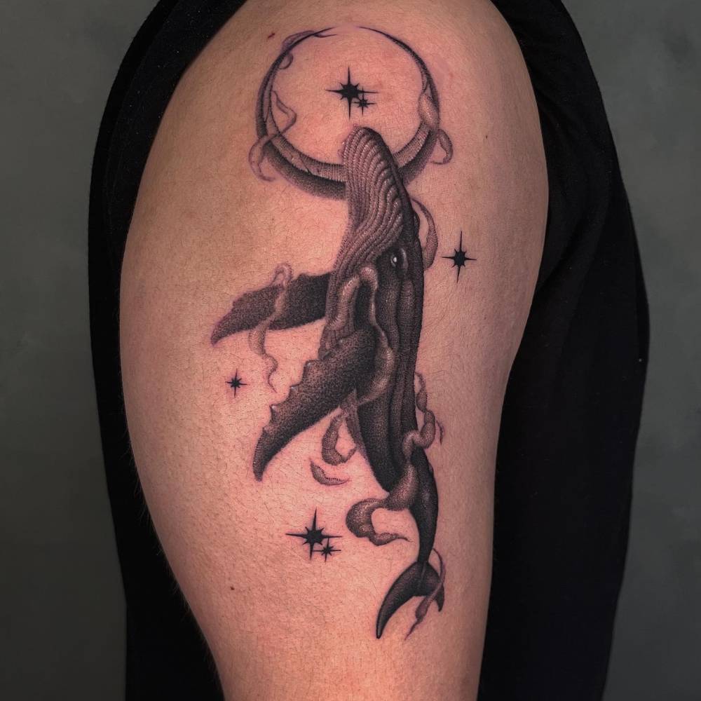Whale tattoo in blackwork style done on the upper arm.
