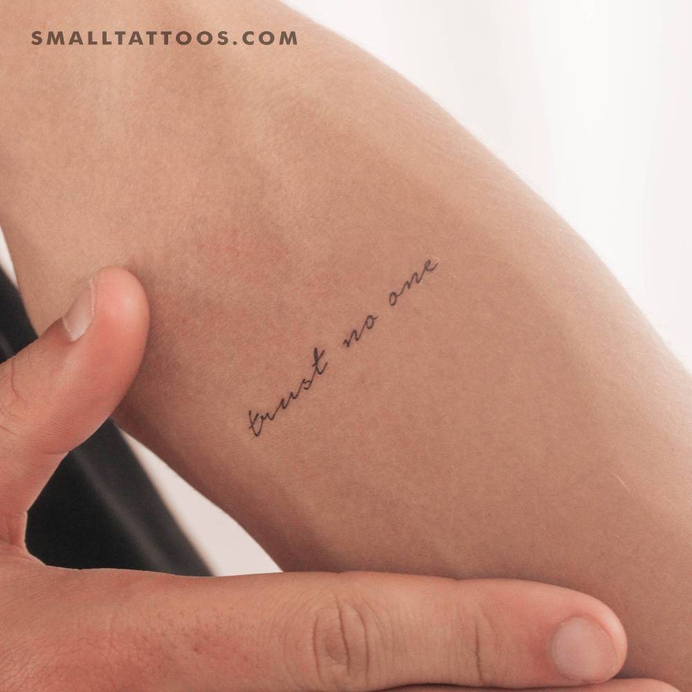 Handwritten font "trust no one" temporary tattoo located on the inner forearm.