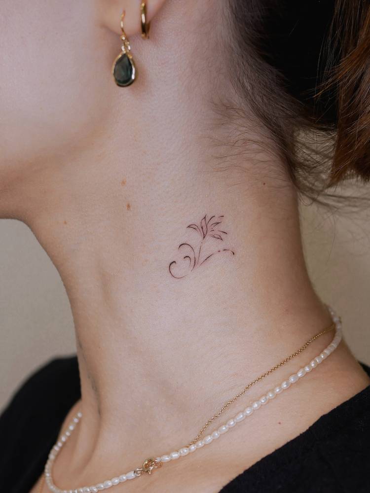 Ornamental flower tattoo in fine line style located on the neck.